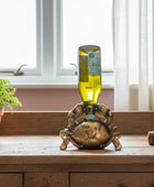 Decorative bottle holder shaped like a crab on a wooden surface with a window in the background.