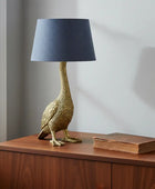 Decorative goose-shaped table lamp with a dark blue shade on a wooden surface.