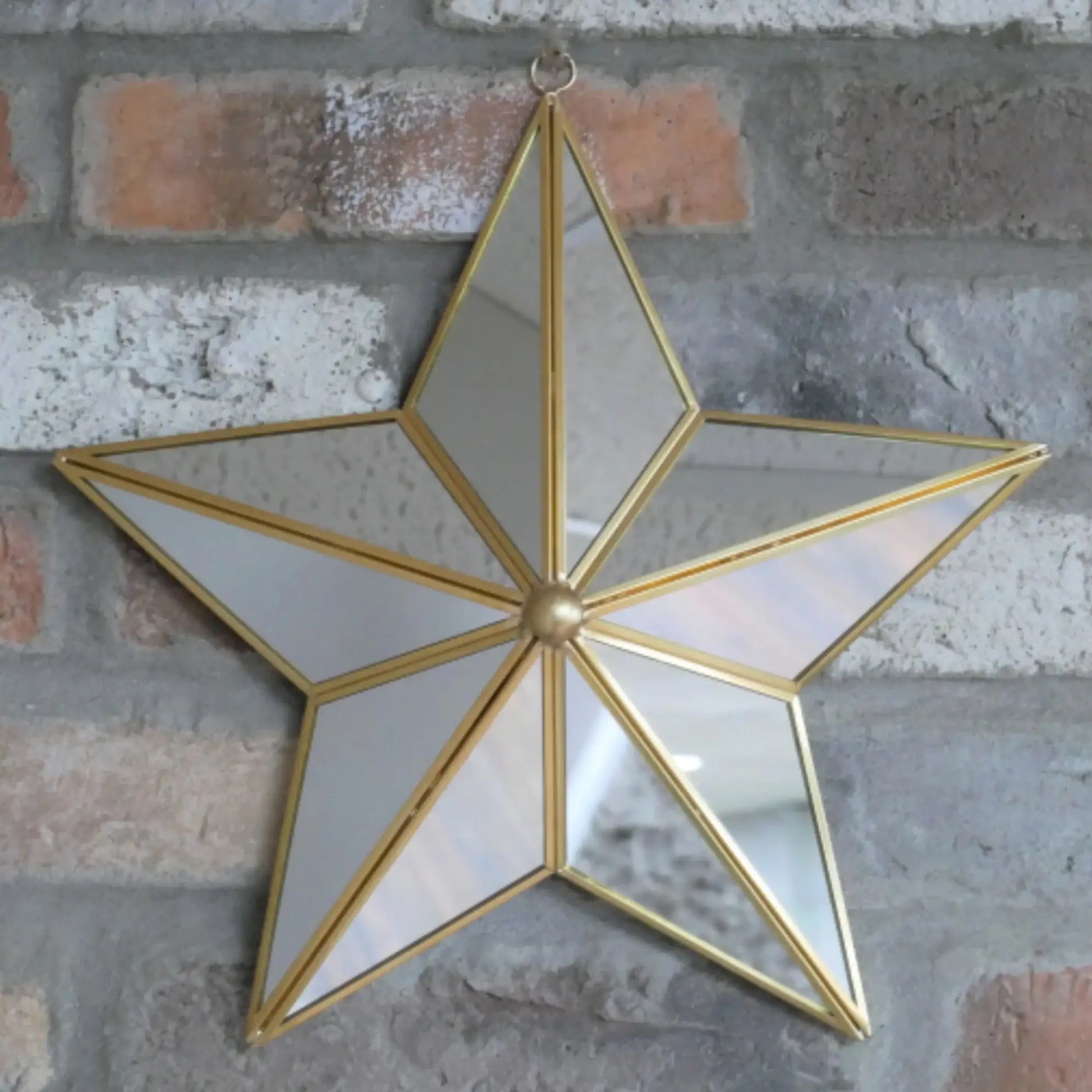 Star-shaped mirror with gold frame on a brick wall