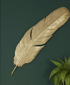 Decorative gold feather on a dark green background with a plant
