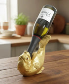 Gold fish-shaped wine bottle holder with a wine bottle on a wooden table.