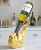 Gold fish-shaped wine bottle holder with a wine bottle inside on a white background