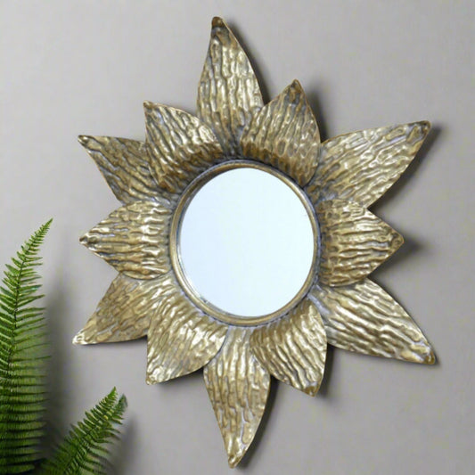 Decorative gold sun-shaped mirror on a brick wall