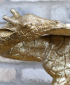 Gold metallic lizard-shaped object on a textured surface