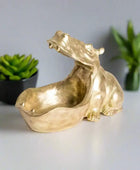 Gold-colored sculpture of a stylized animal on a white background