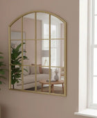 Gold-framed mirror on a brick wall