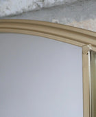 Gold-framed mirror on a white wall with a textured gray background