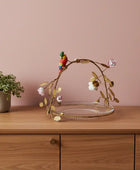 Decorative plate with gold leaf design, bird figurine, and flowers on a white background