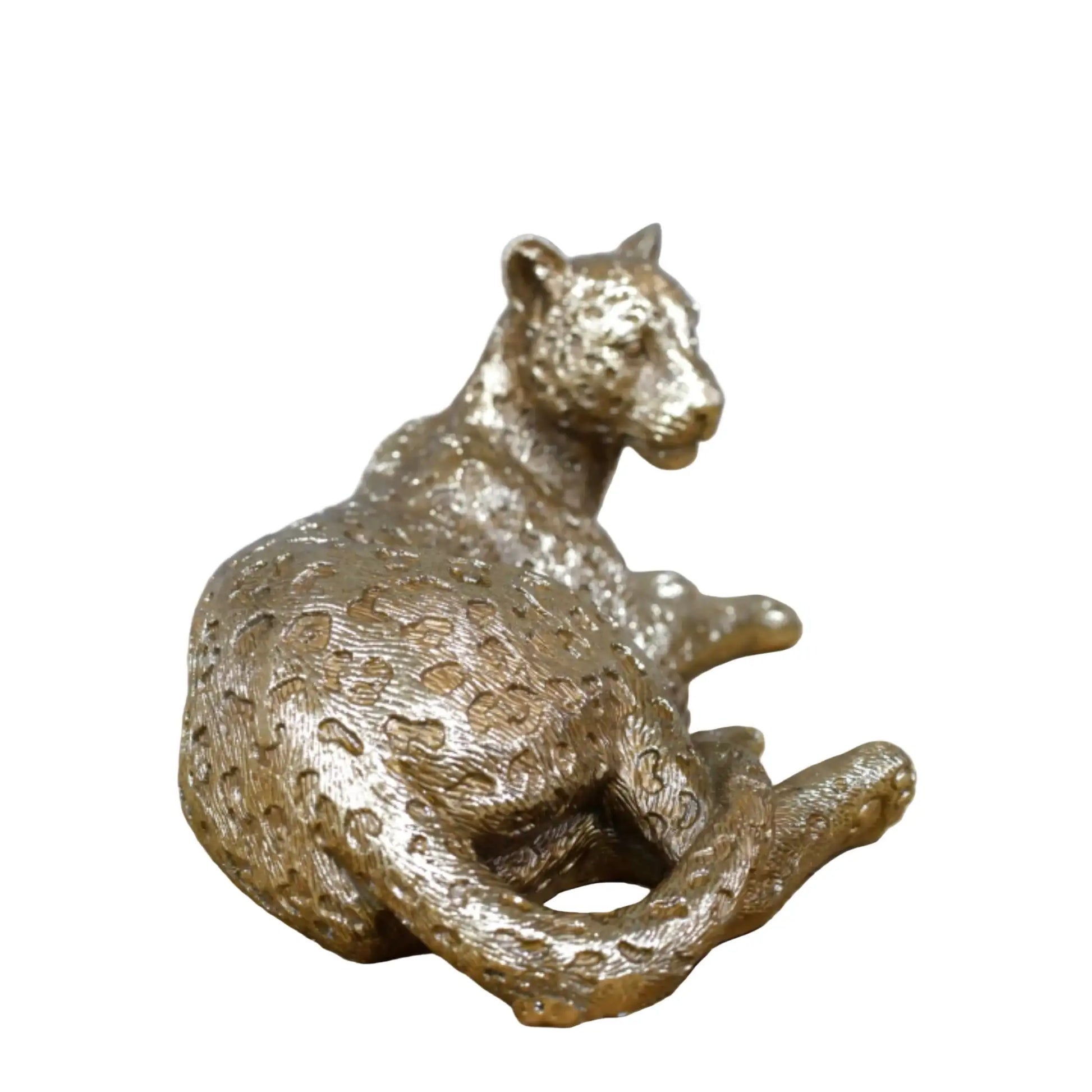Bronze panther figurine on a wooden surface with a stone wall background
