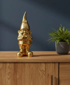 Gold gnome figurine on a wooden surface with a dark blue background