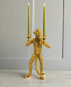 Gold monkey candle holder with two candles on a white background