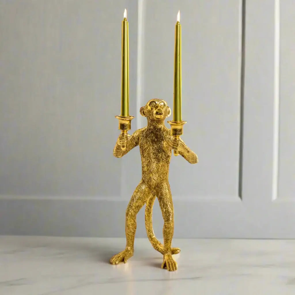 Gold monkey candle holder with two candles on a white background