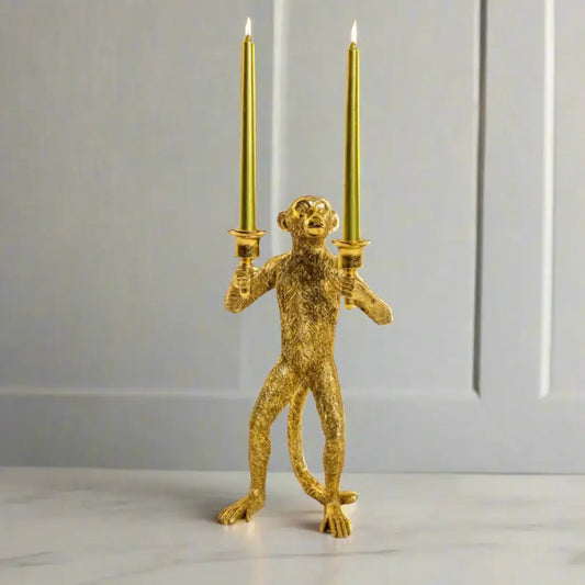 Gold monkey candle holder with two candles on a white background
