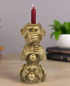 Gold monkey candle holder with a red candle on a gray background