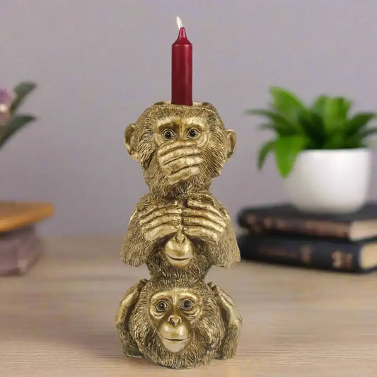 Gold monkey candle holder with a red candle on a gray background