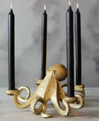 Gold octopus-shaped candle holder with four black candles on a gray background