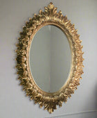 Decorative gold mirror with intricate design on a plain wall