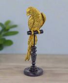 Decorative gold parrot figurine on a black stand against a white background