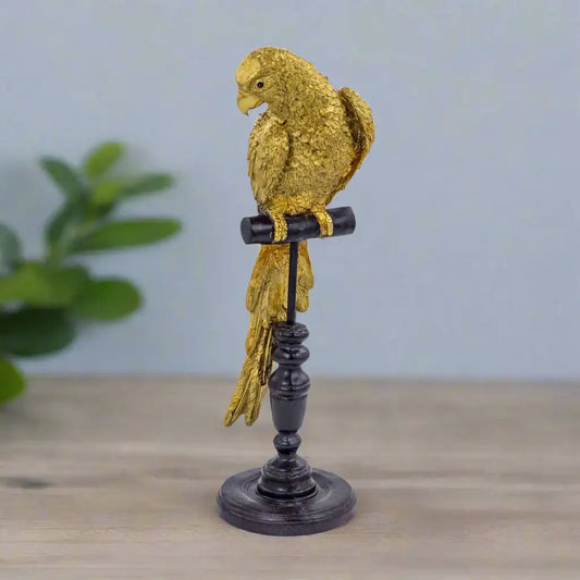 Decorative gold parrot figurine on a black stand against a white background