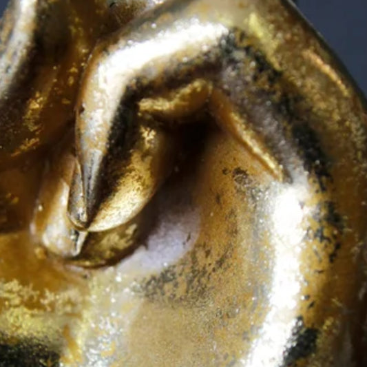 Close-up of a metallic gold object with a sculpted curved form and dark oxidized or patina details.