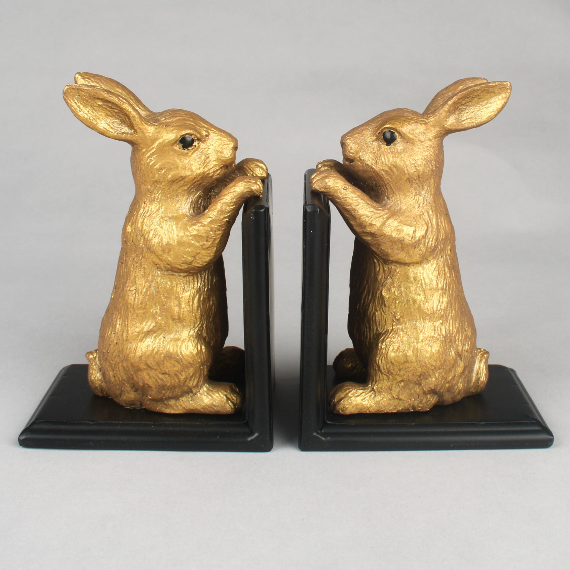 Gold rabbit bookends on black bases against a gray background