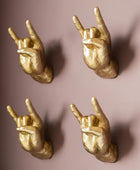 Four gold hands making rock-on gestures on a brown background