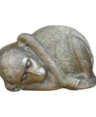 Bronze sculpture of a cat curled up on a wooden surface with a blurred background