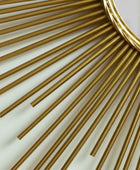 Close-up of a gold decorative mirror with sunburst design on a light background