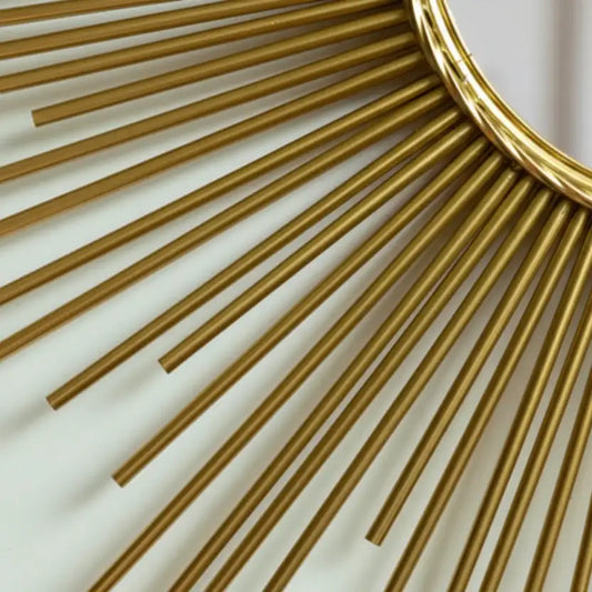 Close-up of a gold decorative mirror with sunburst design on a light background