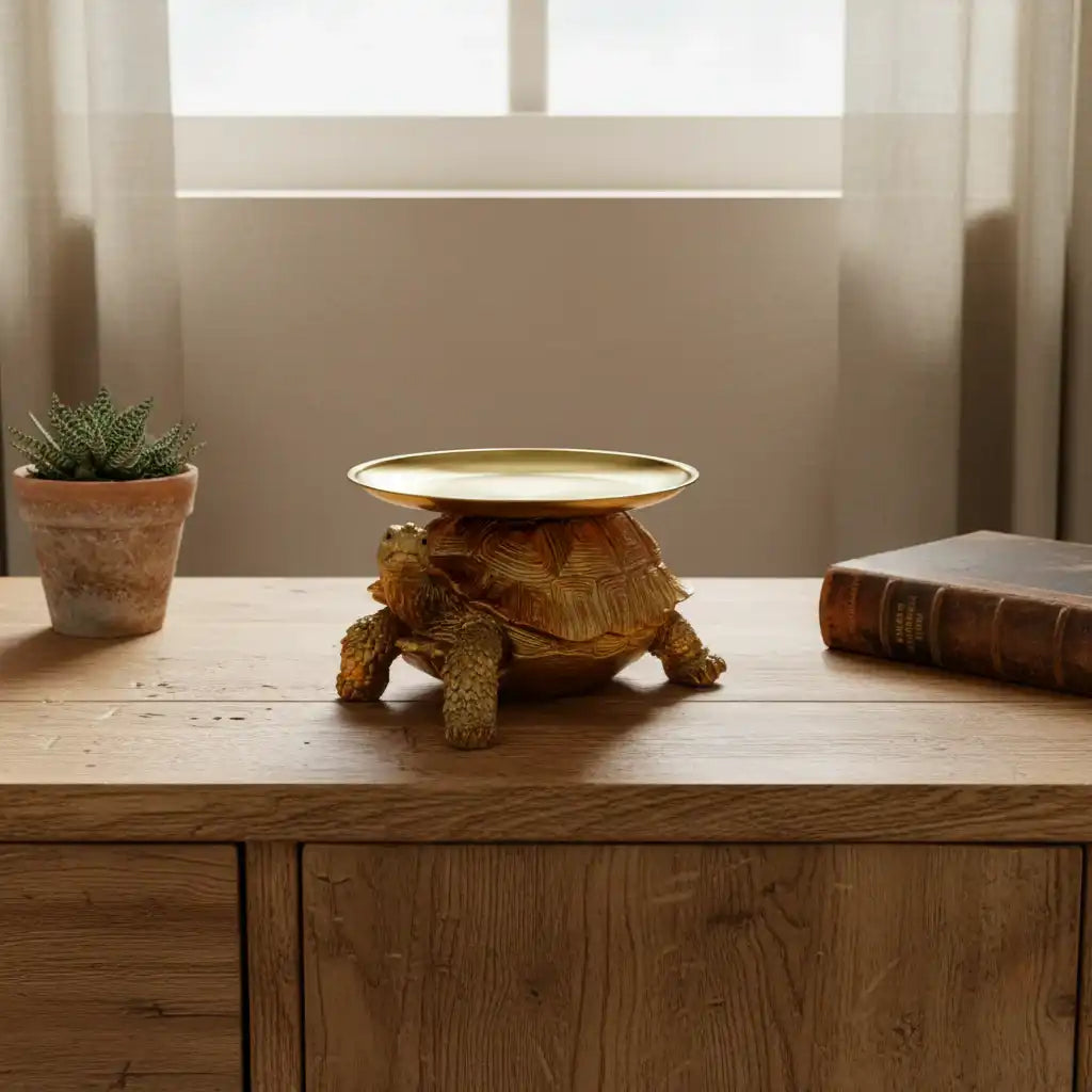 Tortoise-shaped lamp on a wooden surface with a plant and book in the background