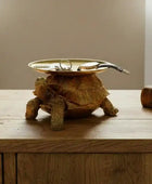Decorative turtle figurine with a dish on a wooden surface