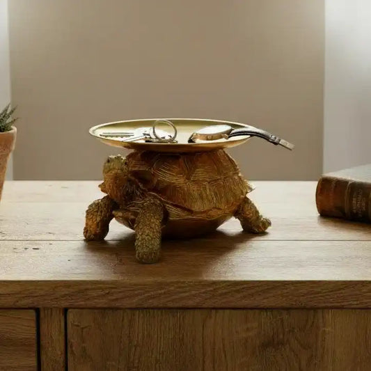 Decorative turtle figurine with a dish on a wooden surface