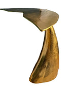 Gold side table on a wooden floor with a plant and basket in the background