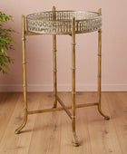 Gold side table with decorative tray on a wooden floor against a pink wall