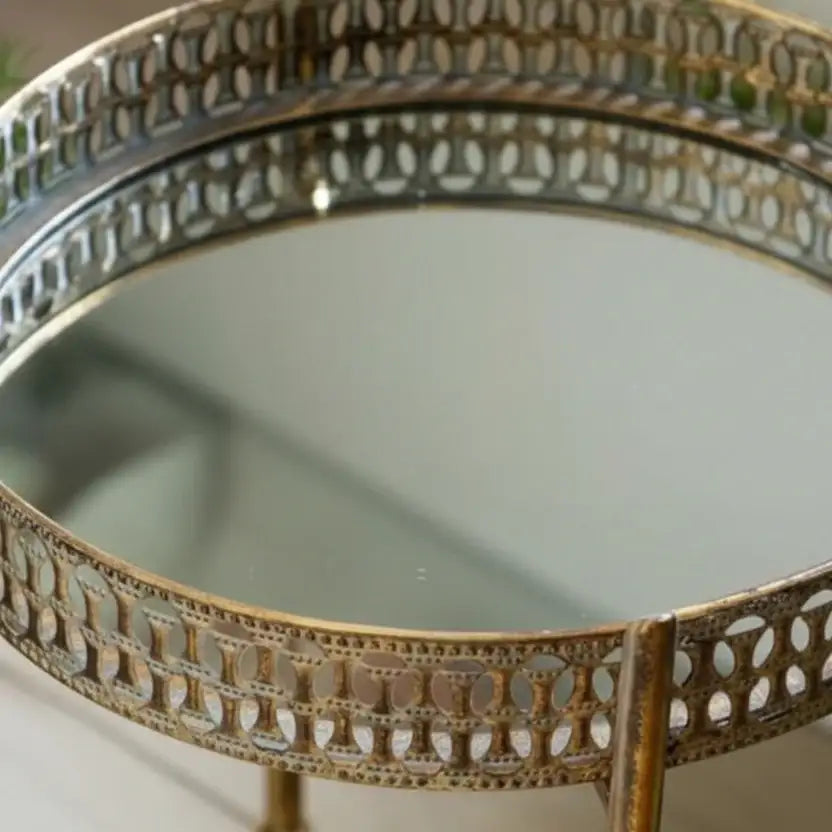 Decorative round mirror with intricate gold frame on a white background