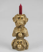 Gold monkey candle holder with a red candle on a gray background