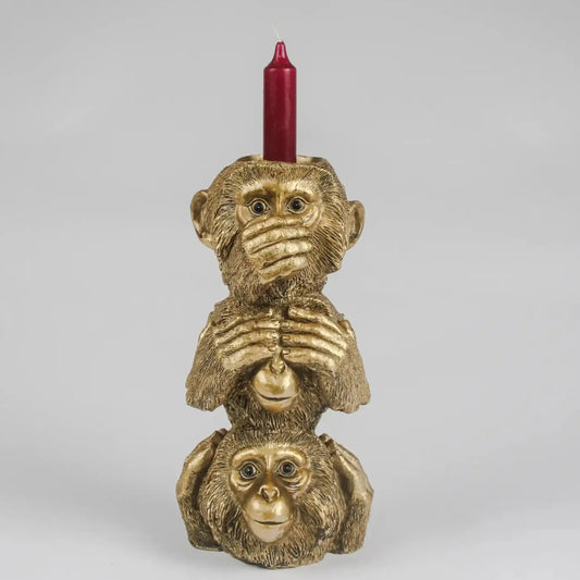 Gold monkey candle holder with a red candle on a gray background