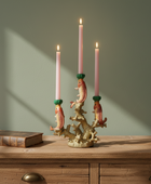 Decorative candle holder with fish design on a wooden surface against a green wall.
