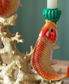 Decorative candle holder with a goldfish design on a green background
