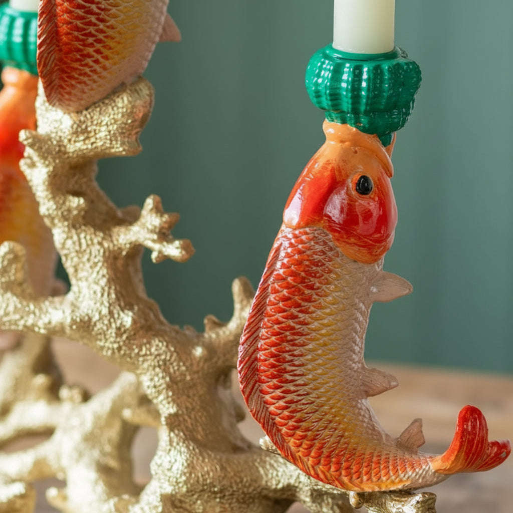 Decorative candle holder with a goldfish design on a green background