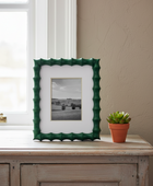 Framed picture on a wooden surface with a potted plant