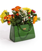 Green handbag filled with colorful flowers on a white background