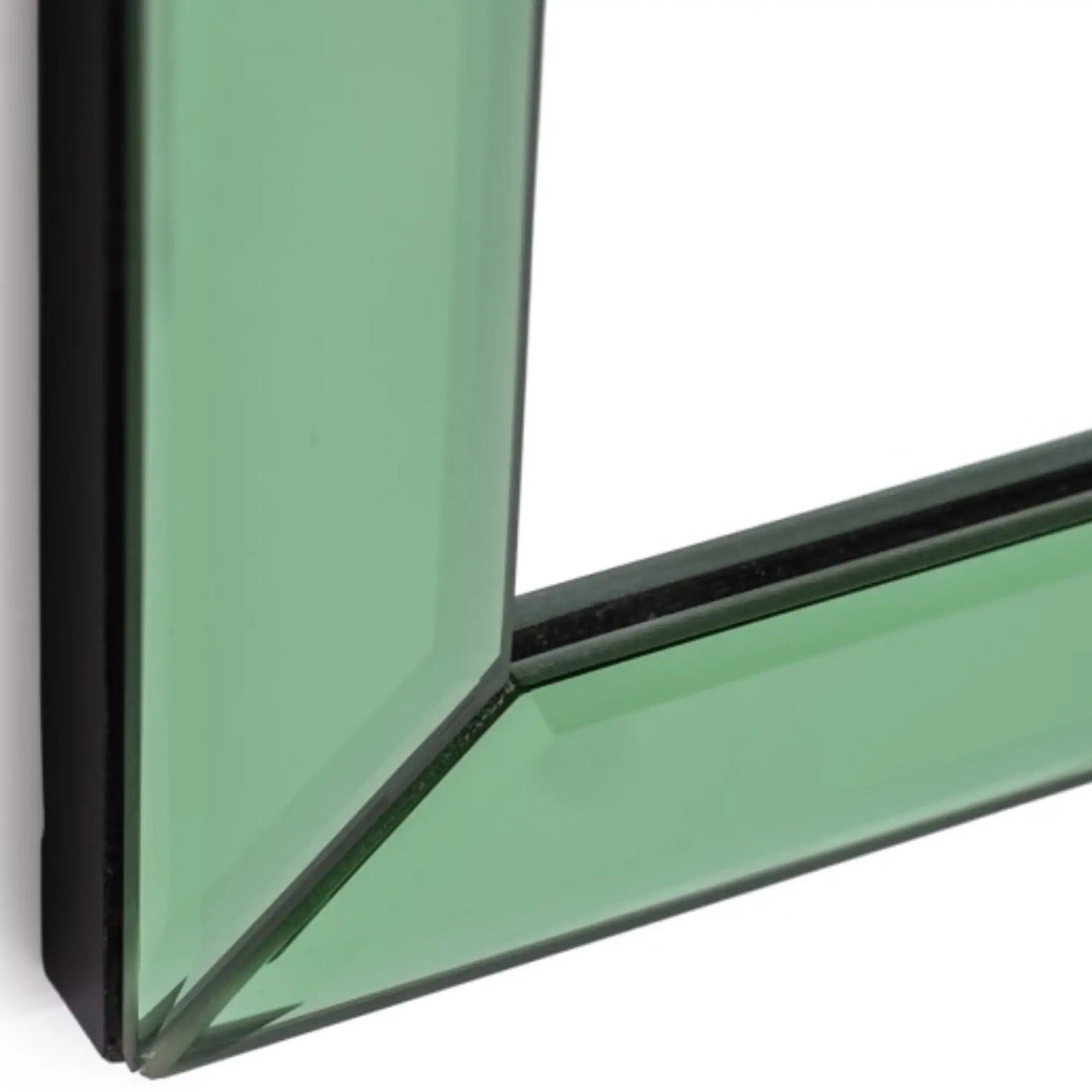 Close-up of a corner where green glass meets black frame on a white background