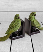 Two green parrot bookends on a light wooden surface
