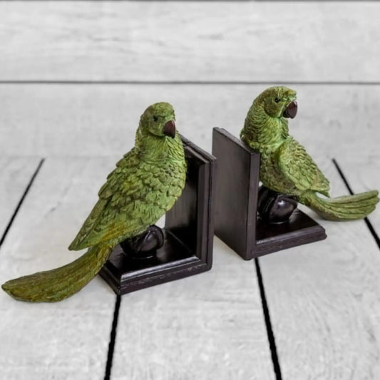 Two green parrot bookends on a light wooden surface