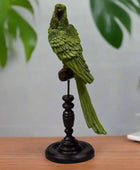 Green parrot figurine on a black stand against a white background
