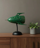 Green rocket-shaped lamp on a wooden surface with a plant in the background