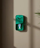 Green wall clock with fish design on a beige wall