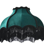 A vintage-style teal velvet lampshade with black fringe trim along the scalloped edge.