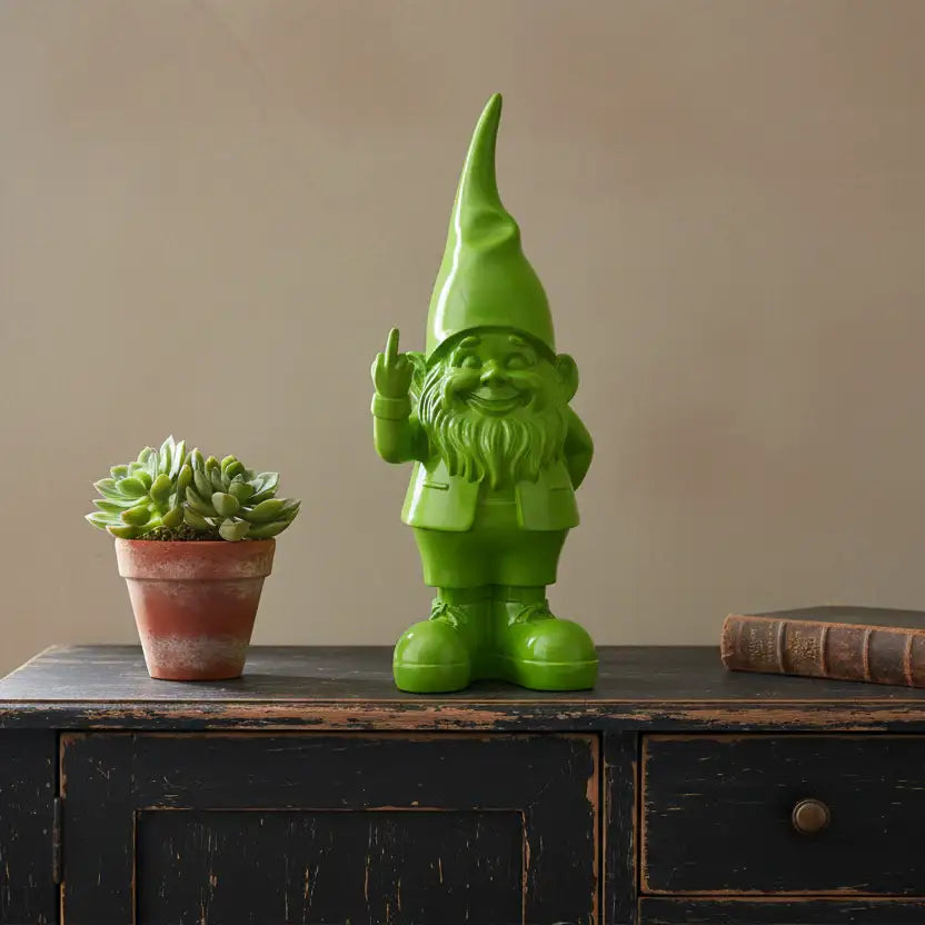 Green gnome figurine and potted succulent on a wooden surface with a beige wall background